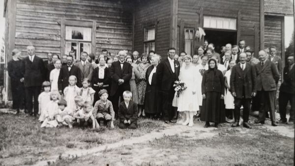 Juhlaväki on kokoontunut talon eteen Suonenjoen Metsälässä 1920-luvun lopulla otetussa kuvassa. Kuvassa vasemmalla näkyvän lapsijoukon keskellä etummaisena istuva pikkupoika on Sirpa Hyytiäisen isä Esko Markkanen. (Kuvaaja: Sirpa Hyytiäisen kotialbumi)