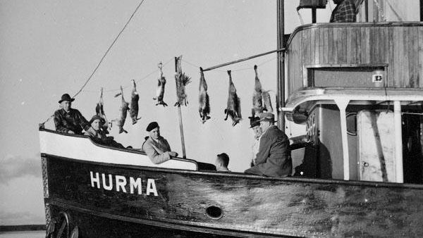 Kaukaan metsästysseuralaiset saaliineen Hurma -laivan kannella. Kaukaan metsästysseura järjesti vuosittain metsästysretken Saimaan saariin. Retkeä kutsuttiin Pömpelijahdiksi. (Kuva: Kaj Ramm-Schmidtin kokoelma/Lusto)