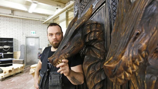 Puustikki Oy:n Jarkko Pilvinen ja juuri asiakkaalle valmistuva kaappi. Runko on mäntyä, lohikäärmeenpäät on tehty koivusta.  (Kuvaaja: Sami Karppinen)