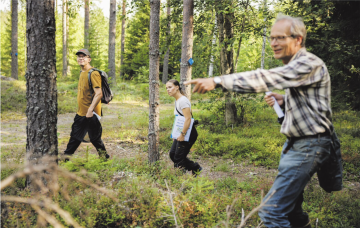 Hyrian opettaja Heikki Kiuru (edessä), tutkija Janne Heliölä ja Pölymetsä-hankkeen projektipäällikkö Sara Turunen etsivät oppilaitoksen metsistä pölyttäjille mieleisiä rakennepiirteitä. Kiuru on bongannut rusokukkajäärän. (Kuvaaja: Seppo Samuli)