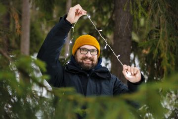strongTorbjörn Granbergstrong sai idean elävien joulukuusien vuokrauksesta vuonna 2019 ja vuokrasi ensimmäiset kuuset vuotta myöhemmin. Koska yrityksen omia kuusia ei kuvaushetkellä ollut, Granberg mallailee valonauhaa lähimetsän kuuseen.  (Kuvaaja: Seppo Samuli)